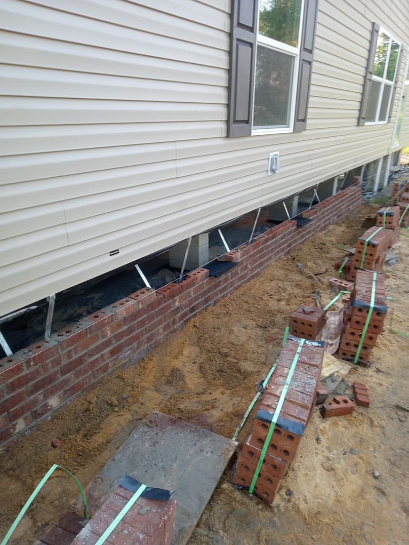 Brick skirt installation in progress showing step-by-step professional construction process