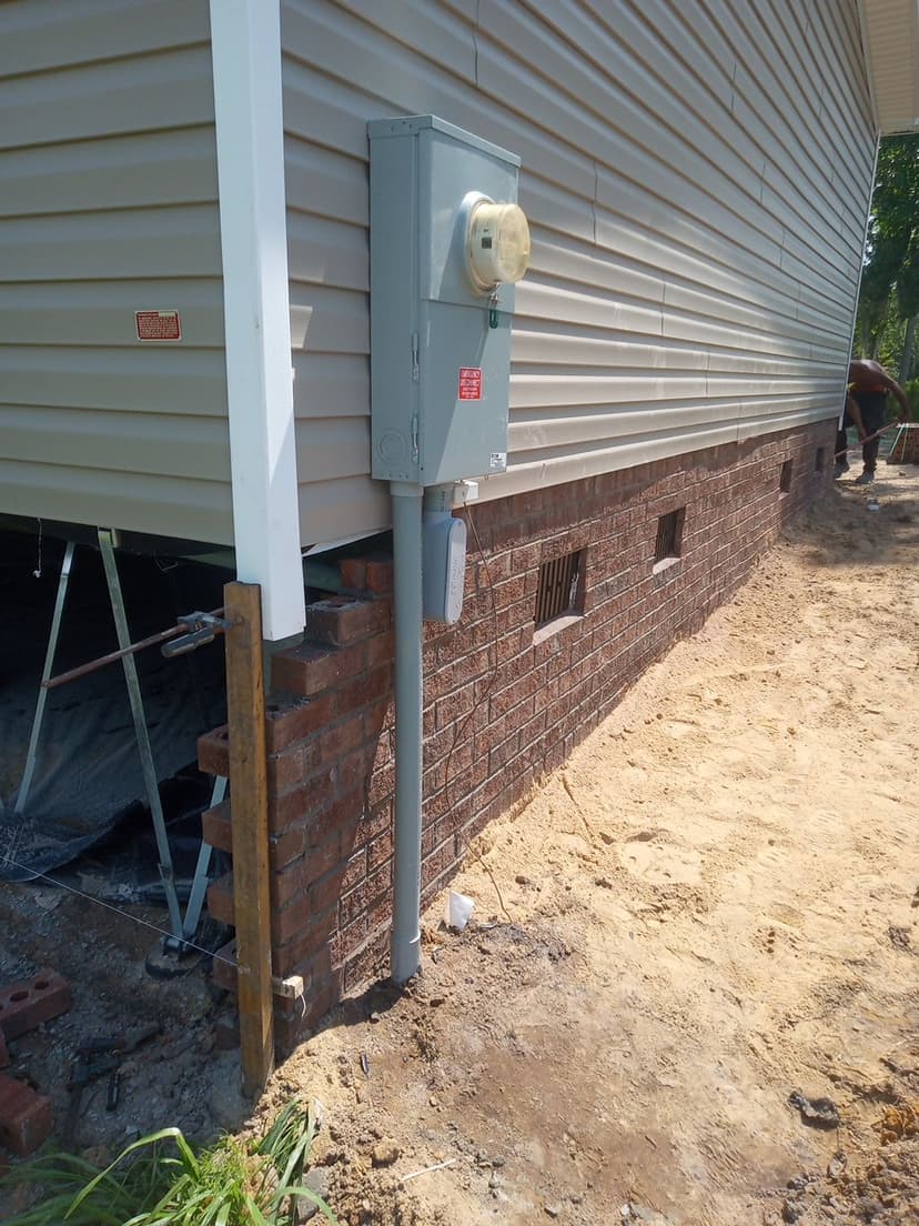 Complete home exterior brick skirt installation with integrated utility connections