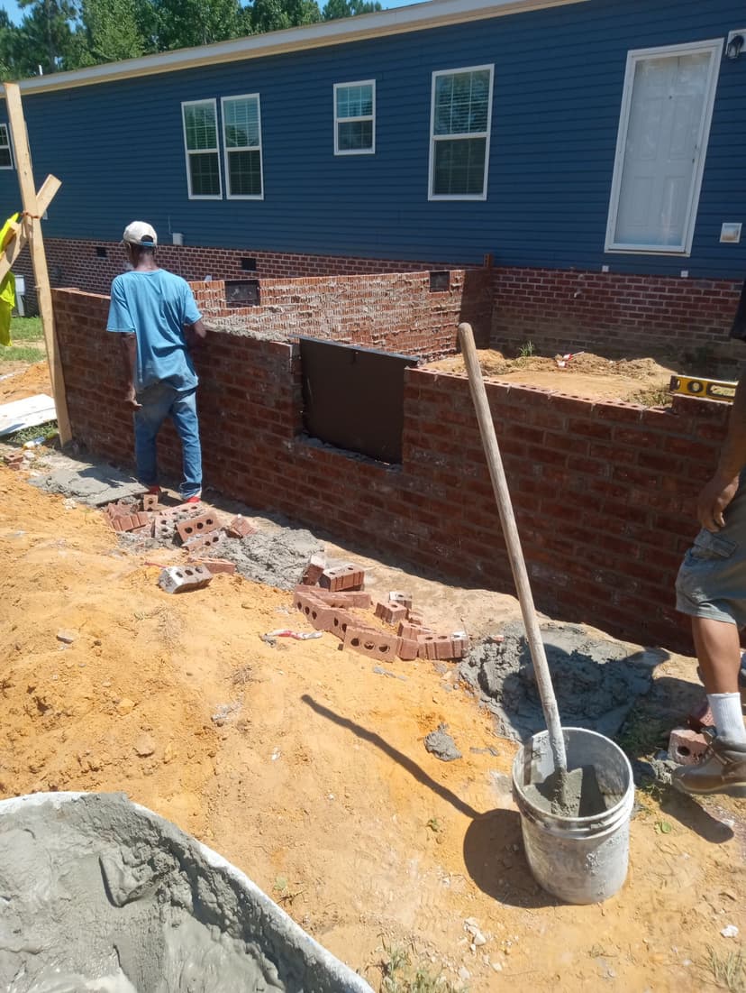 Professional mason working on brick foundation wall showing hands-on craftsmanship and expertise